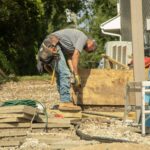 Construction worker bending over to nail down deck boards