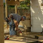 Construction worker cutting boards with a saw.