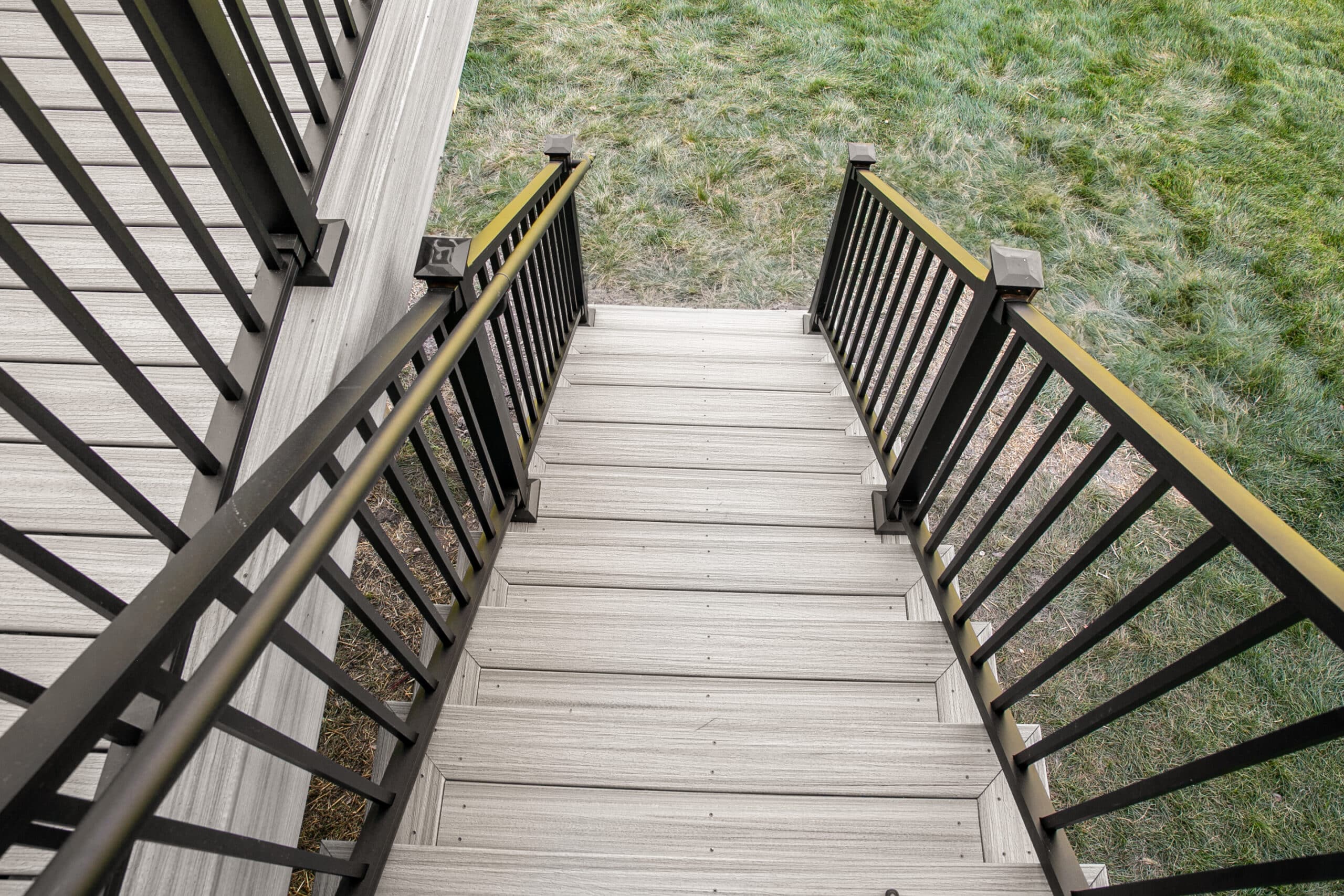 View a new deck staircase with black railings.