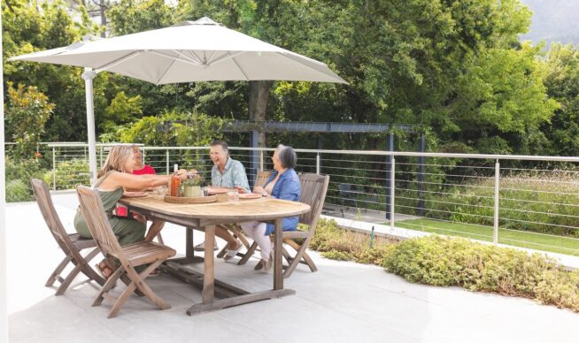 a family sitting at a patio table on a concrete deck. 