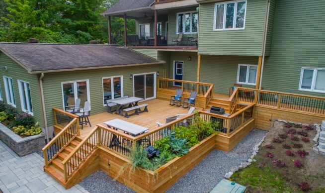 aerial view of a large wooden deck connected to a green hosue.
