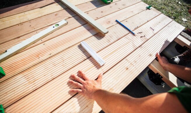 View of a man measuring deck boards.