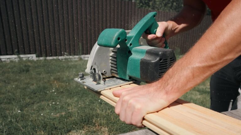 Close up of a man cutting deck boards with an electric saw.