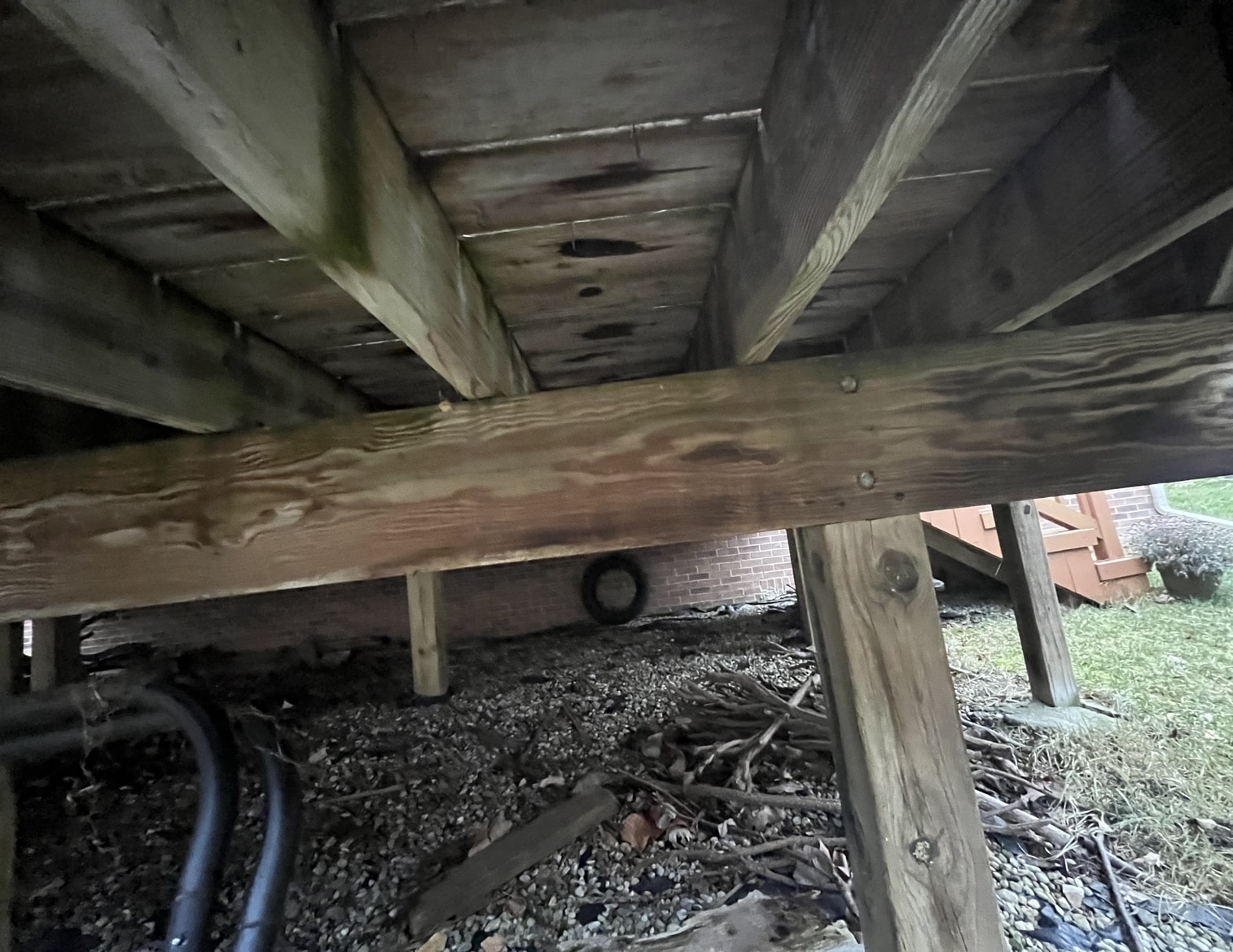 before image of underneath an old deck that needs replaced
