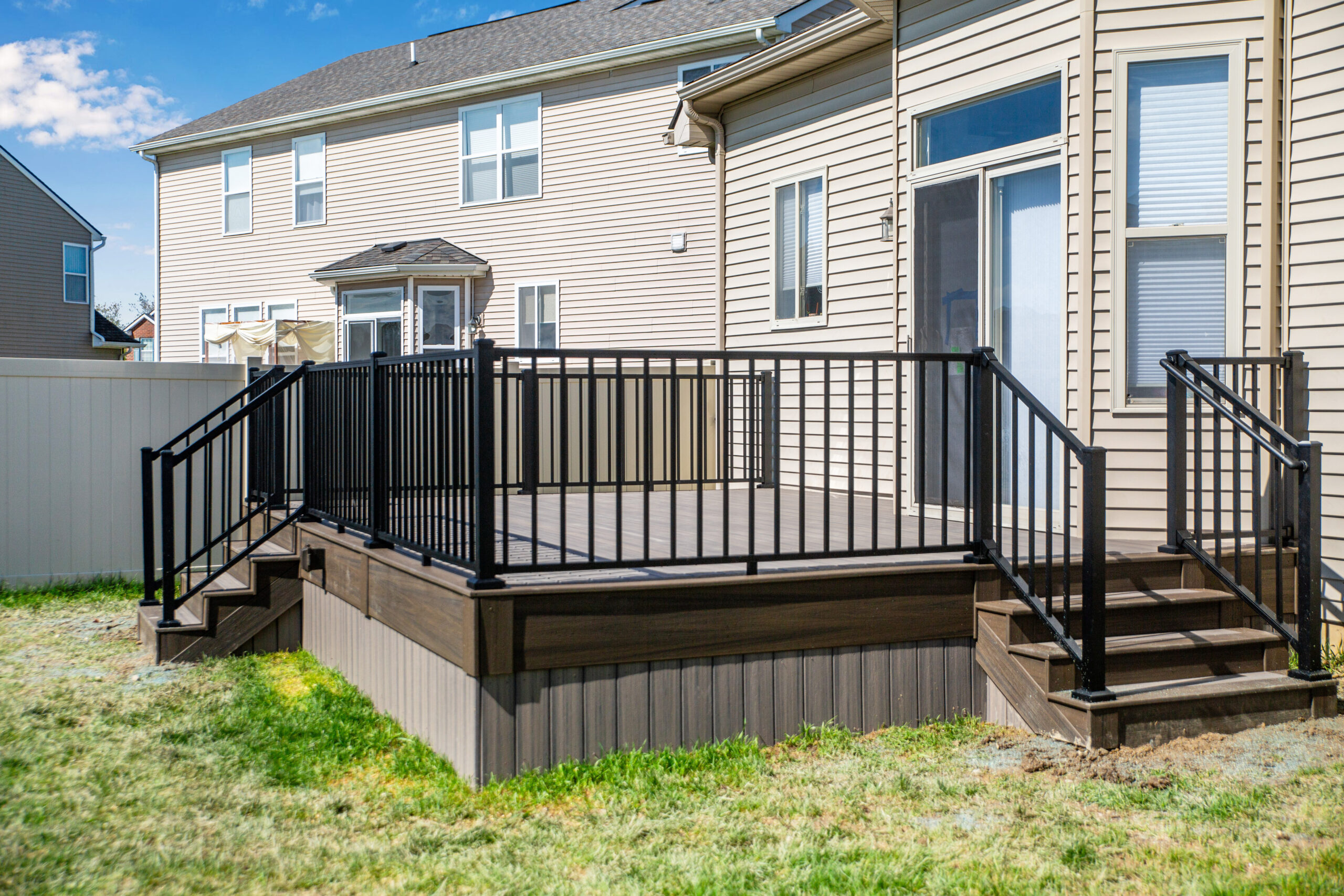 Outside view of a home with a new gray deck with black railings.
